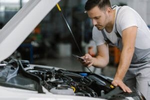 A man inspects the engine of a car, representing the work of mobile mechanics in action.