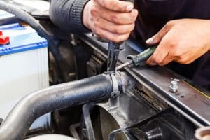 In a garage, a man is diligently working on an engine, with various tools and equipment nearby.